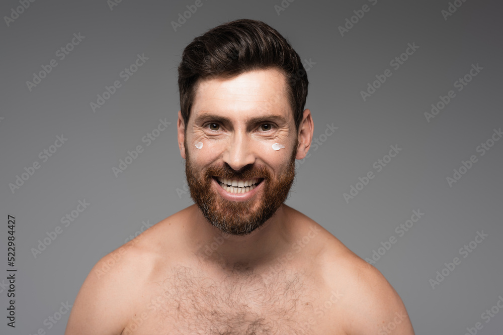 cheerful and bearded man with cream on face smiling isolated on grey. cheerful and bearded man with cream on face smiling isolated on grey.