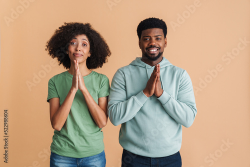 Black man and woman smiling and praying with hands together