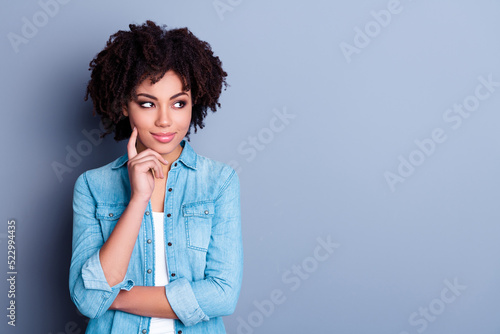 Photo of dreaming pleased woman curls wear jeans outfit make choice arms finger hold cheekbones isolated on gray color background