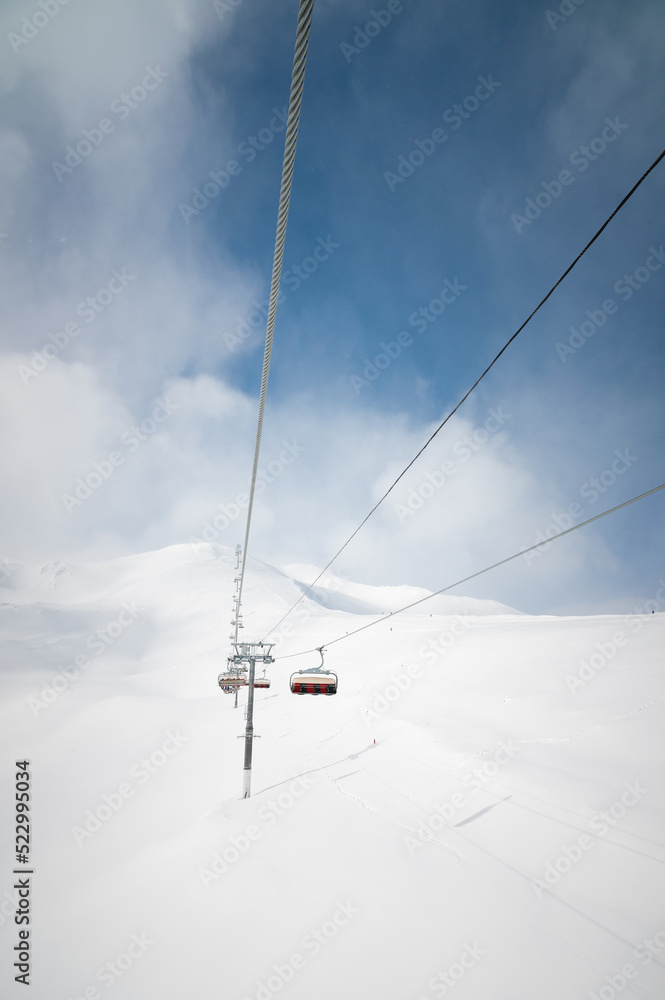 ski lift high in the clouds against the backdrop of snow-capped mountains