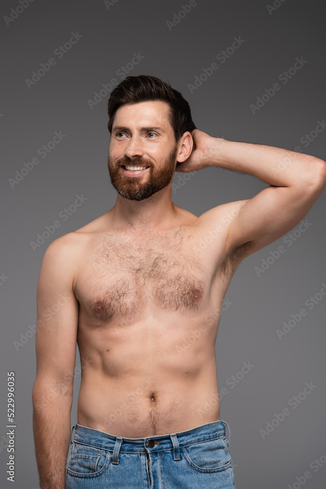 shirtless and bearded man looking away while smiling isolated on grey. shirtless and bearded man looking away while smiling isolated on grey.