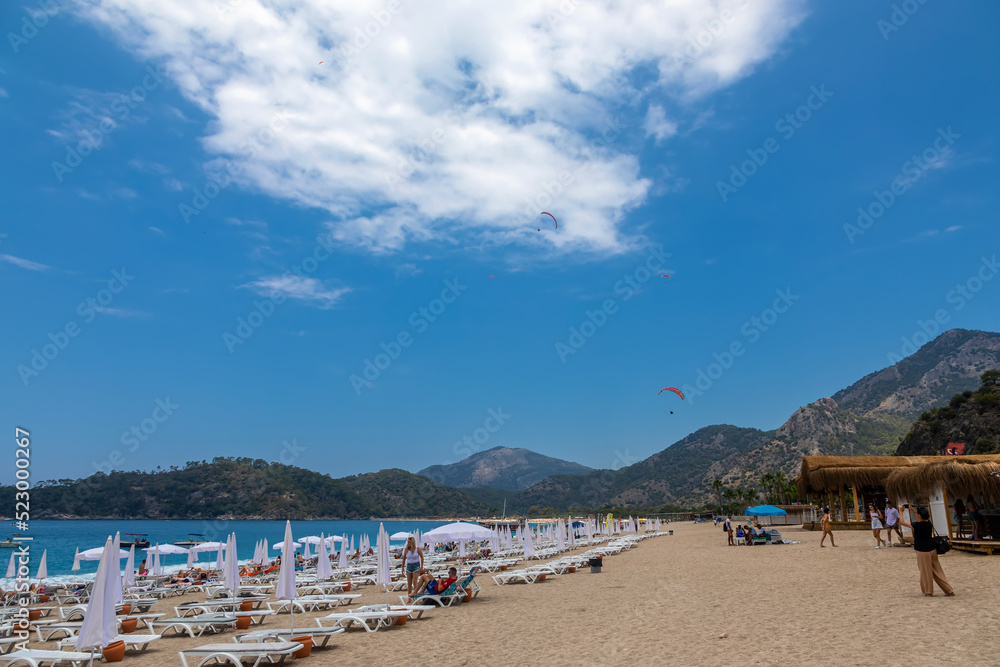 Beautiful and colorful beach. High mountains. White clouds in the blue sky. Colorful sea shore.