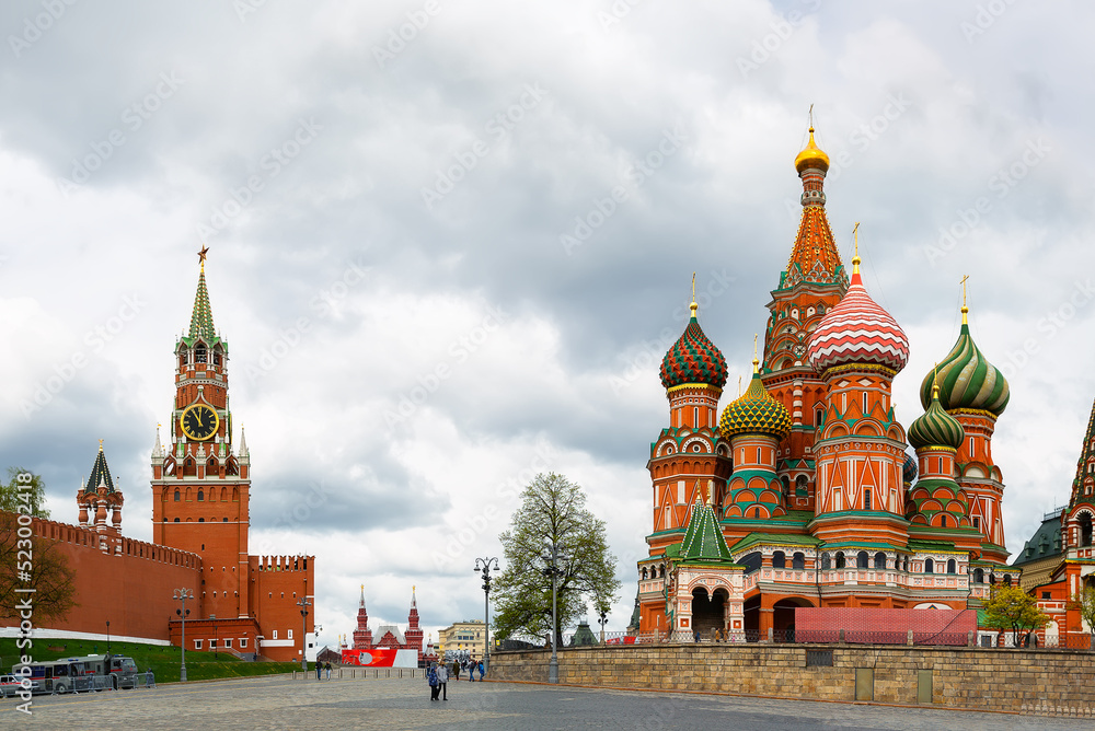 St. Basil's Cathedral on Red square and Moscow Kremlin with Spasskaya tower on a dramatic cloudy sky background.