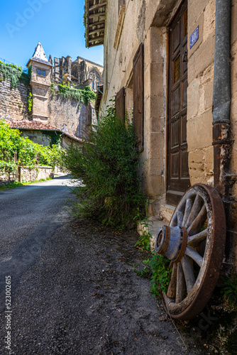 Old style street with a wooden wheel on the foreground of the one most beautiful french villages of Saint-Antoine-l'Abbaye
