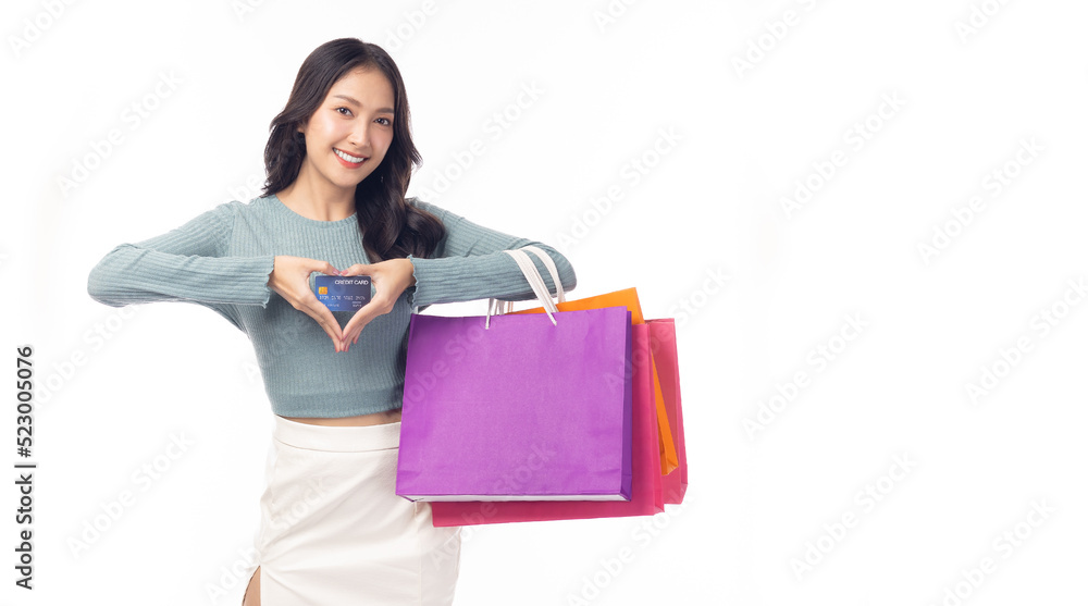 Trendy young Asian woman hold plastic credit card and shopping bags Showing heart with two hands, love sign Beautiful shopping girl love shopping looking at camera Isolated on white background Trendy young Asian woman hold plastic credit card and shopping bags Showing heart with two hands, love sign Beautiful shopping girl love shopping looking at camera Isolated on white background