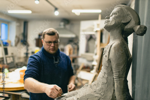 Man sculptor creates sculpt bust clay human woman sculpture. Statue craft creation workshop.