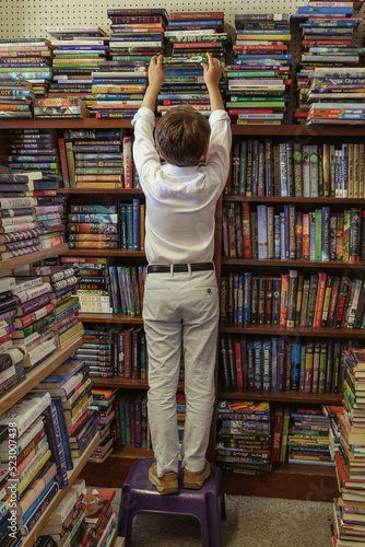 child with stack of books in store