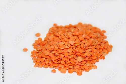 Red lentils (Lens culinaris) heaped and isolated on a white background, space for text.