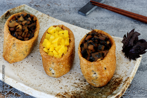 Inari Sushi (inarizushi) with takuan (pickled daikon) and bamboo shoots marinated with shiso leaves. photo