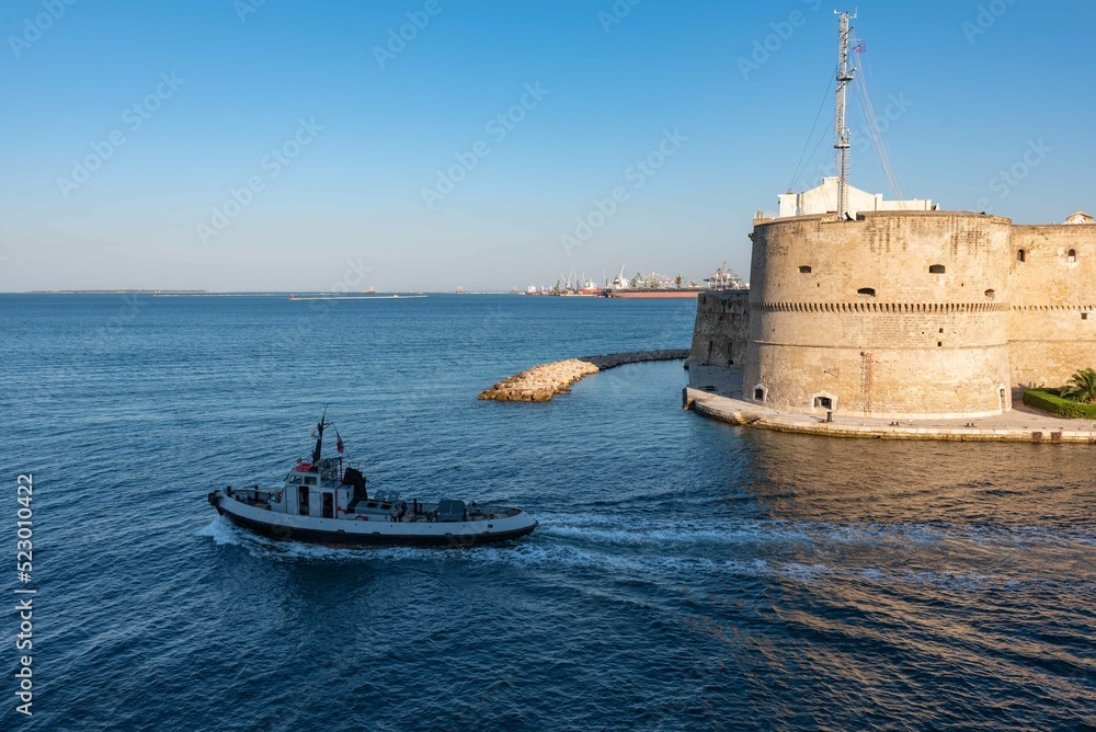 Small Tug  thet exits from the Taranto Canalboat in summer, in front of the Aragonese Castle