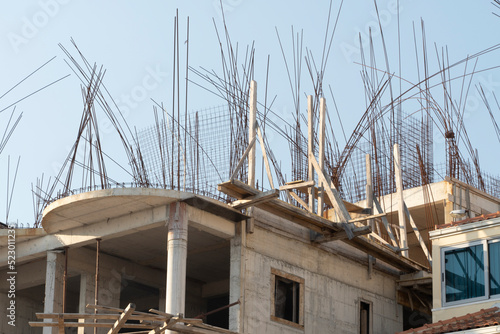 steel reinforcement sticking out of a concrete unfinished building on a construction site.