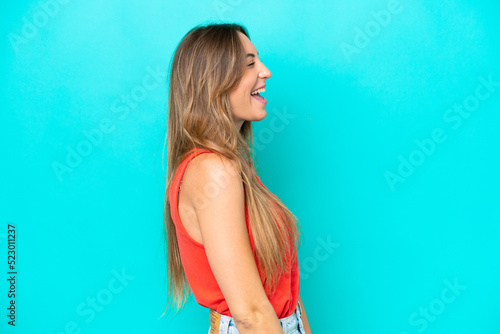 Young caucasian woman isolated on blue background laughing in lateral position