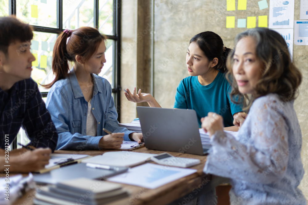 Group of young colleagues meeting with a senior female manager in the office to discuss their experience working on a company project. Group of young colleagues meeting with a senior female manager in the office to discuss their experience working on a company project.