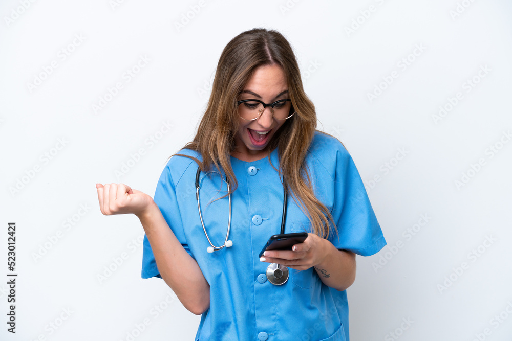 Young surgeon doctor woman isolated on blue background surprised and sending a message Young surgeon doctor woman isolated on blue background surprised and sending a message