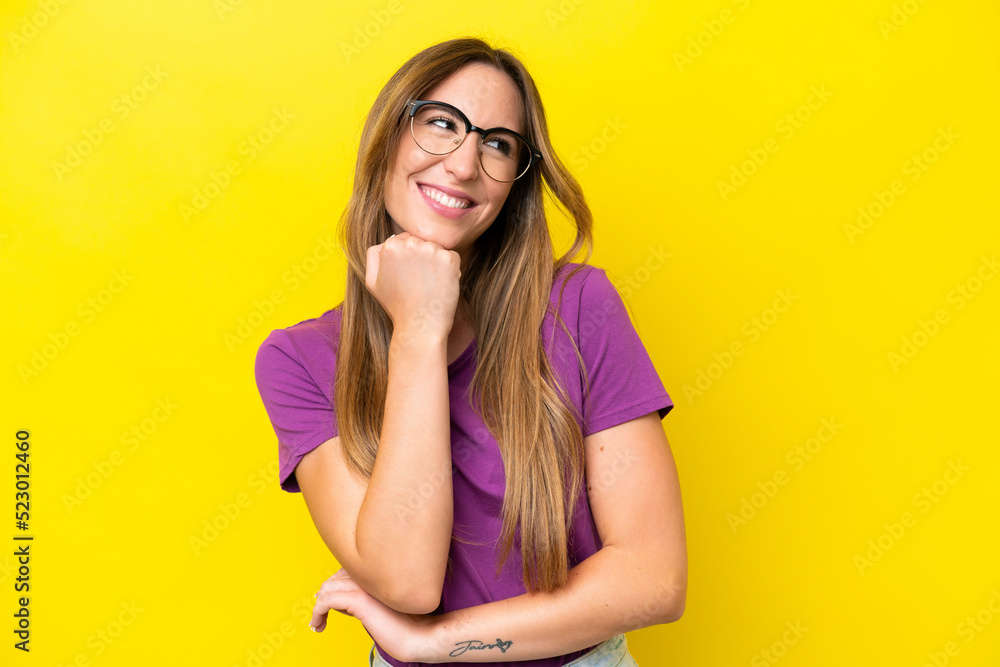 Young caucasian woman isolated on yellow background With glasses and thinking while looking up Young caucasian woman isolated on yellow background With glasses and thinking while looking up