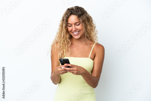 Girl with curly hair isolated on white background sending a message with the mobile