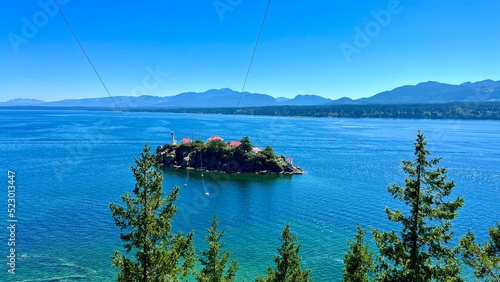 Chrome Island small near Vancouver Island has white houses with red roofs and a single lighthouse view from Denman island to Hornby island pacific ocean coniferous trees blue sea. High quality photo