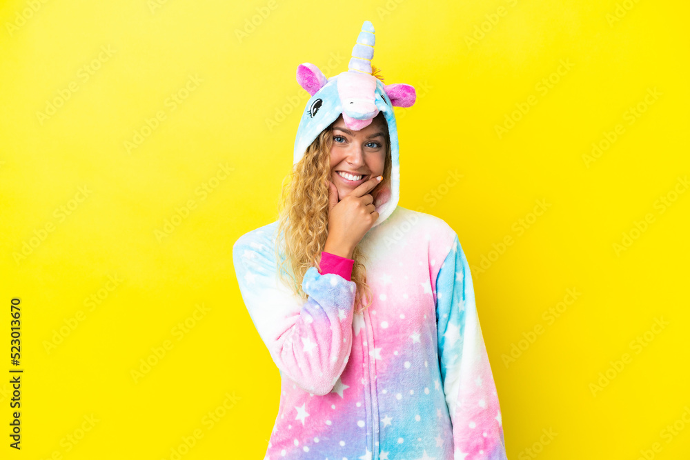 Girl with curly hair wearing a unicorn pajama isolated on yellow background smiling Girl with curly hair wearing a unicorn pajama isolated on yellow background smiling