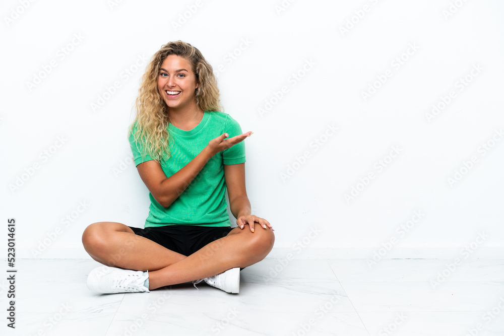 Girl with curly hair sitting on the floor presenting an idea while looking smiling towards Girl with curly hair sitting on the floor presenting an idea while looking smiling towards