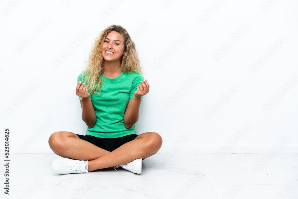 Girl with curly hair sitting on the floor making money gesture Girl with curly hair sitting on the floor making money gesture