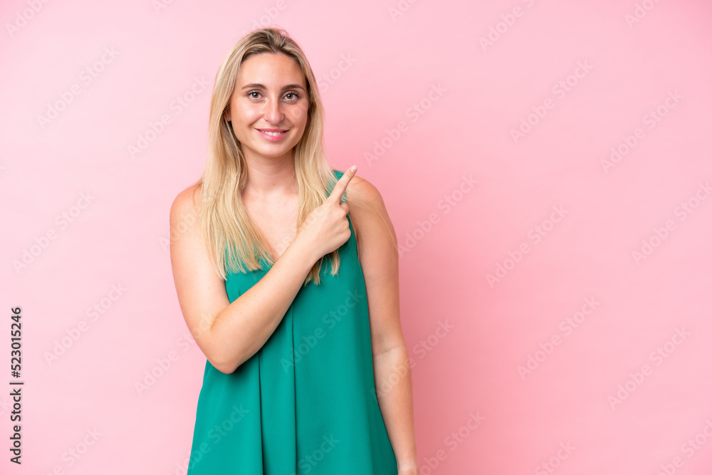 Young caucasian woman isolated on pink background pointing to the side to present a product Young caucasian woman isolated on pink background pointing to the side to present a product