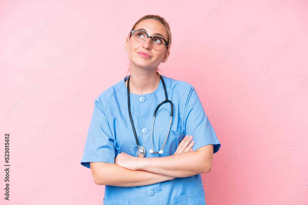 Young surgeon nurse woman isolated on pink background looking up while smiling Young surgeon nurse woman isolated on pink background looking up while smiling