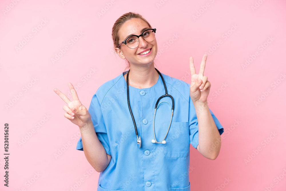 Young surgeon nurse woman isolated on pink background showing victory sign with both hands Young surgeon nurse woman isolated on pink background showing victory sign with both hands