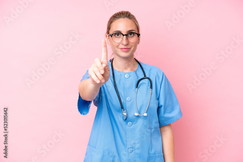 Young surgeon nurse woman isolated on pink background showing and lifting a finger © luismolinero