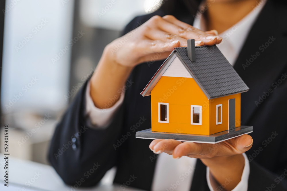 Real estate concept, businesswoman holding a house model, Property insurance and security concept. Real estate concept, businesswoman holding a house model, Property insurance and security concept.