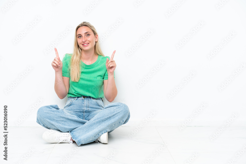 Young caucasian woman sitting on the floor isolated on white background pointing up a great idea Young caucasian woman sitting on the floor isolated on white background pointing up a great idea