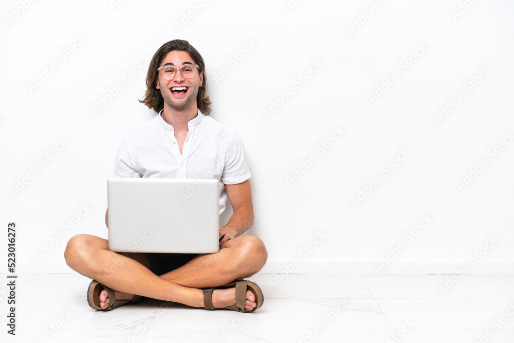 Young handsome man with a laptop sitting on the floor isolated on white background with surprise facial expression Young handsome man with a laptop sitting on the floor isolated on white background with surprise facial expression
