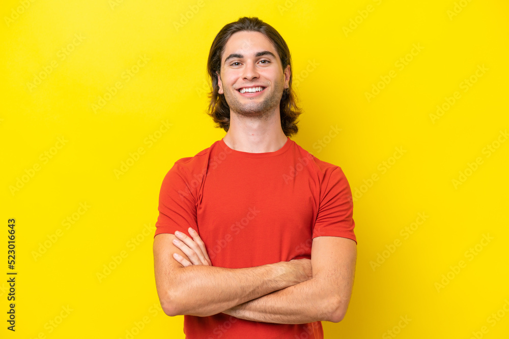 Caucasian handsome man isolated on yellow background keeping the arms crossed in frontal position Caucasian handsome man isolated on yellow background keeping the arms crossed in frontal position