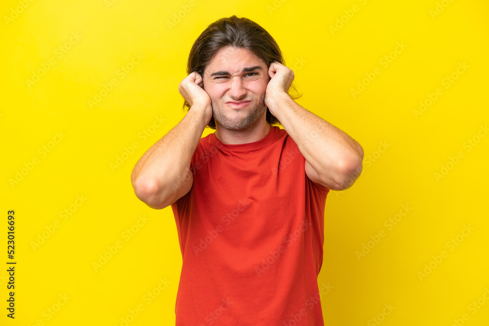 Caucasian handsome man isolated on yellow background frustrated and covering ears Caucasian handsome man isolated on yellow background frustrated and covering ears