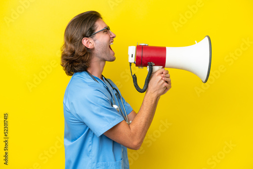 Young surgeon caucasian man isolated on yellow background shouting through a megaphone