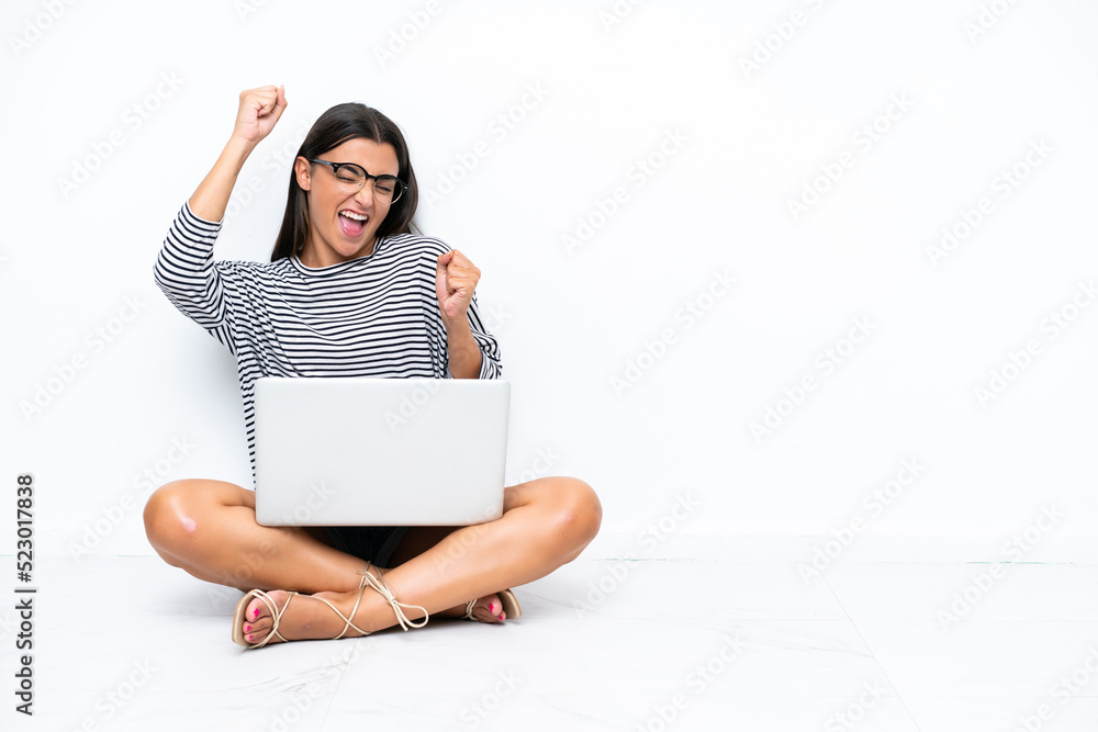 Young caucasian woman with a laptop sitting on the floor celebrating a victory Young caucasian woman with a laptop sitting on the floor celebrating a victory