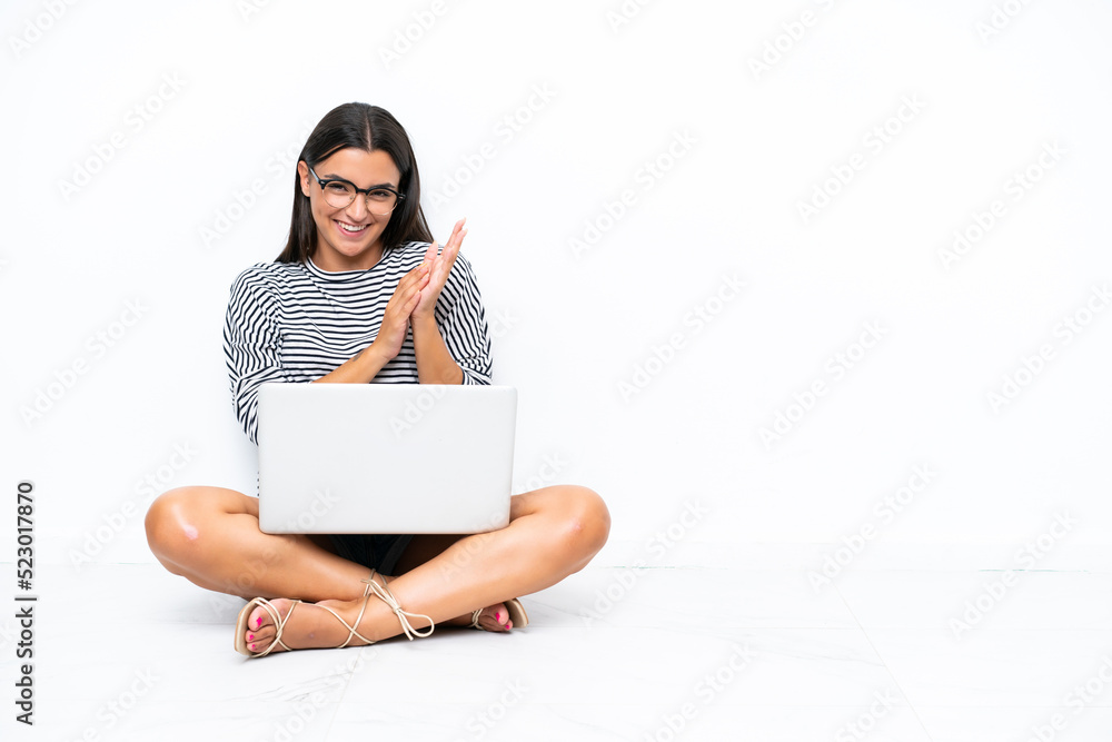 Young caucasian woman with a laptop sitting on the floor applauding after presentation in a conference Young caucasian woman with a laptop sitting on the floor applauding after presentation in a conference