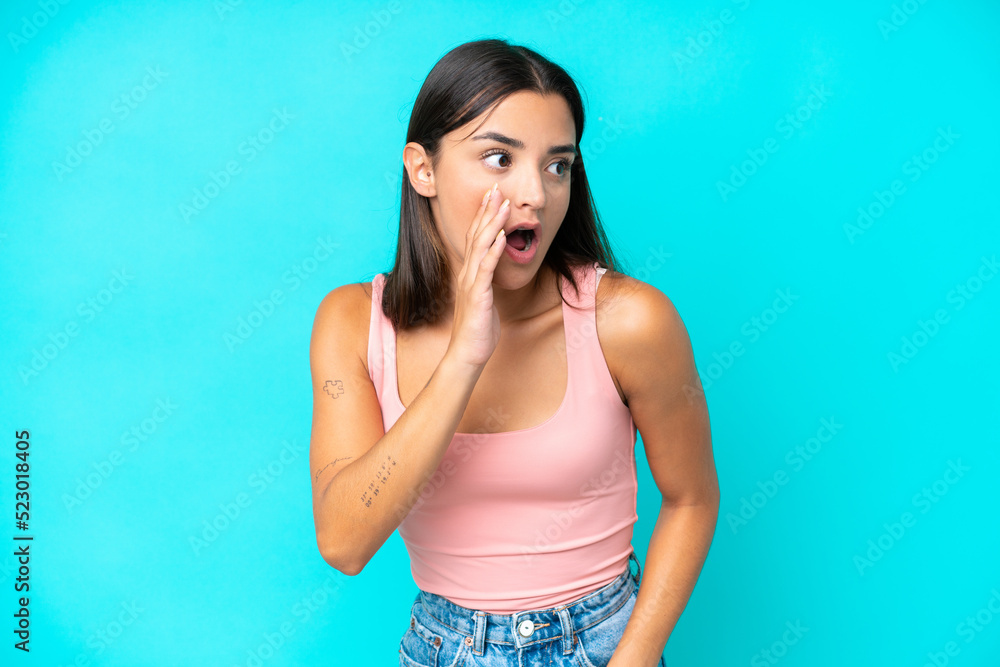 Young caucasian woman isolated on blue background whispering something with surprise gesture while looking to the side Young caucasian woman isolated on blue background whispering something with surprise gesture while looking to the side