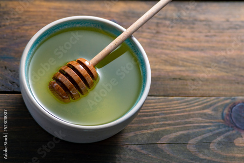 Healthy organic Thick acacia Honey. Healthy organic thick honey dripping from the honey dipper bowl. Sweet dessert background drizzlerwooden table