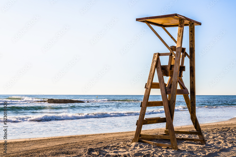 Mediterranean beach with wooden lifeguard chair in sunset time, in Spain. Teal and orange style. Mediterranean beach with wooden lifeguard chair in sunset time, in Spain. Teal and orange style.