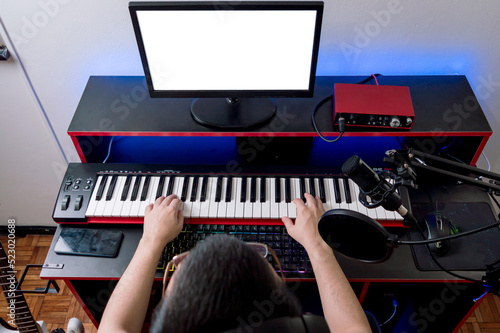 Overhead view of person sitting in home music studio set playing piano recording and producing music