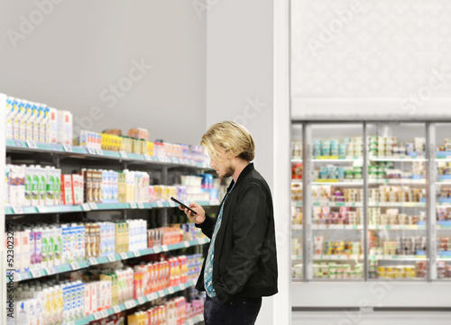  Man choosing frozen food from a supermarket freezer., reading product information