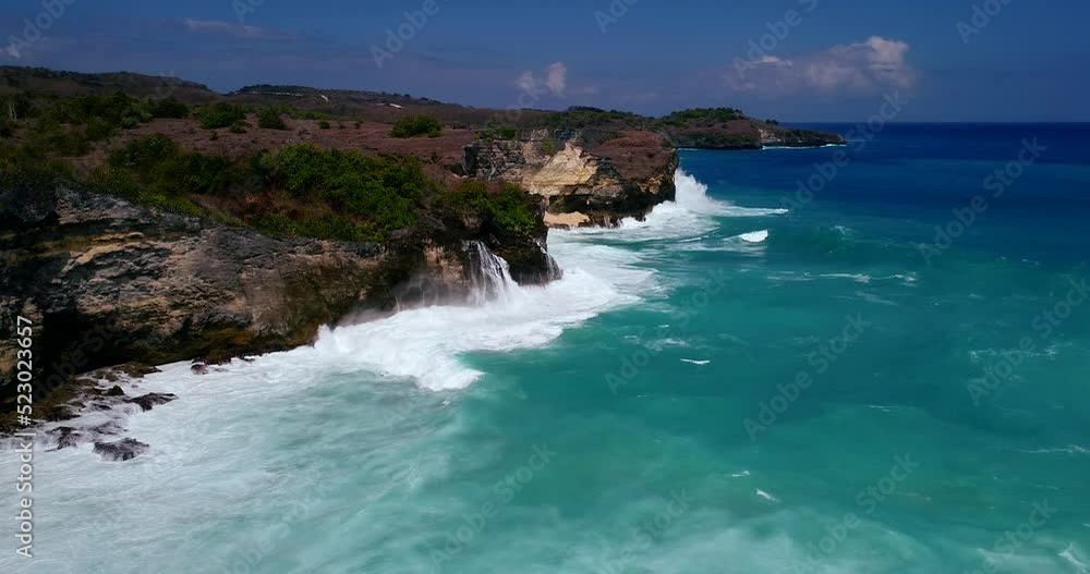 Aerial shot of rocky coast with huge waves crashing against it