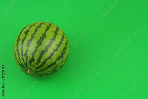 Whole watermelon on green background with copy space for text. 