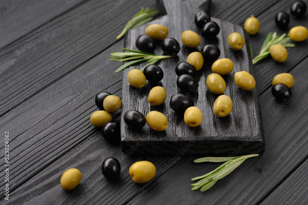 Black and green olives on a dark wooden black background. Black and green olives on a dark wooden black background.