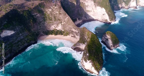 Aerial shot of beach with turquoise water down steep cliff and headland