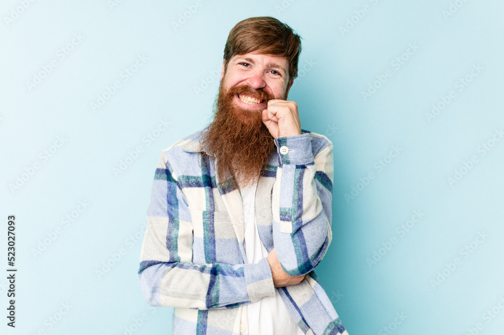 Young caucasian red-haired man isolated on blue background smiling happy and confident, touching chin with hand. Young caucasian red-haired man isolated on blue background smiling happy and confident, touching chin with hand.