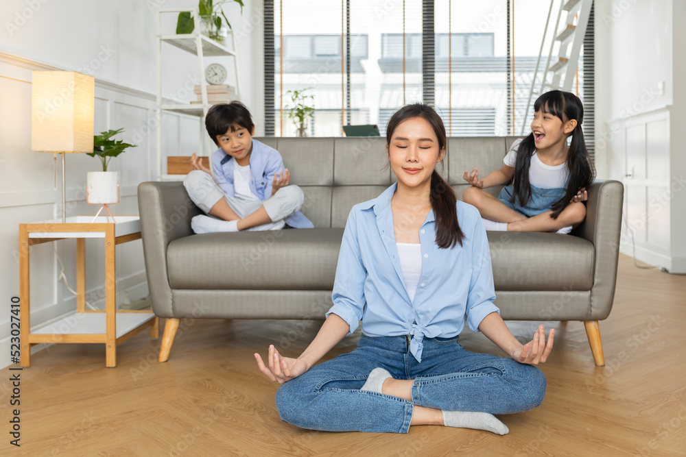 Asian woman with cute funny kid daughter doing yoga exercise at home.Friendly sincere two female generations family relaxing on couch, healthcare concept. Asian woman with cute funny kid daughter doing yoga exercise at home.Friendly sincere two female generations family relaxing on couch, healthcare concept.