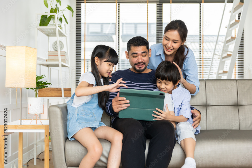 Asian family using tablet, laptop, phone for playing game or movies, relaxing at home for technology lifestyle concept. Asian family using tablet, laptop, phone for playing game or movies, relaxing at home for technology lifestyle concept.