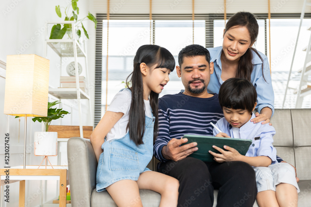 Asian family using tablet, laptop, phone for playing game or movies, relaxing at home for technology lifestyle concept. Asian family using tablet, laptop, phone for playing game or movies, relaxing at home for technology lifestyle concept.