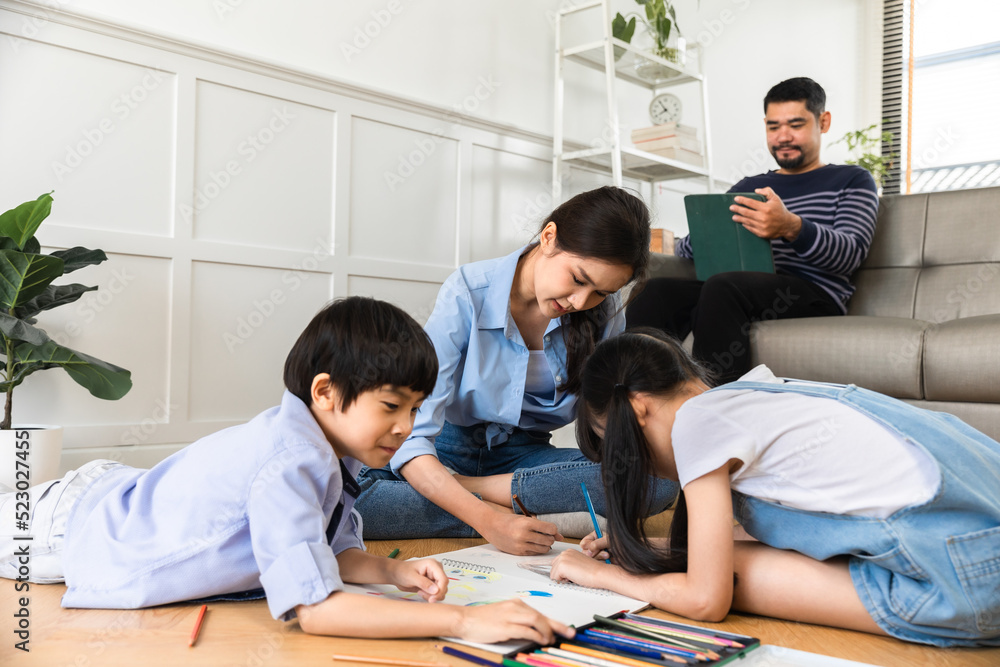 Happy Asian family relaxing on sofa while kid drawing on floor. Little boy girl having fun, friendship between siblings, family leisure time in living room at home. Happy Asian family relaxing on sofa while kid drawing on floor. Little boy girl having fun, friendship between siblings, family leisure time in living room at home.